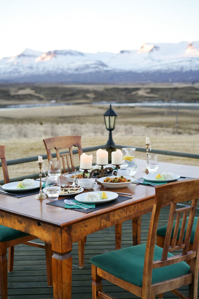 Elegant outdoor dining setup with candles and mountain view at sunset, perfect for fine dining experiences.